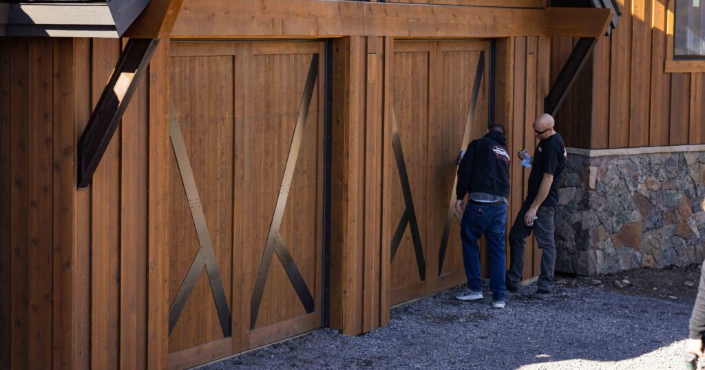 men installing steel detailing to face of custom wood garage door